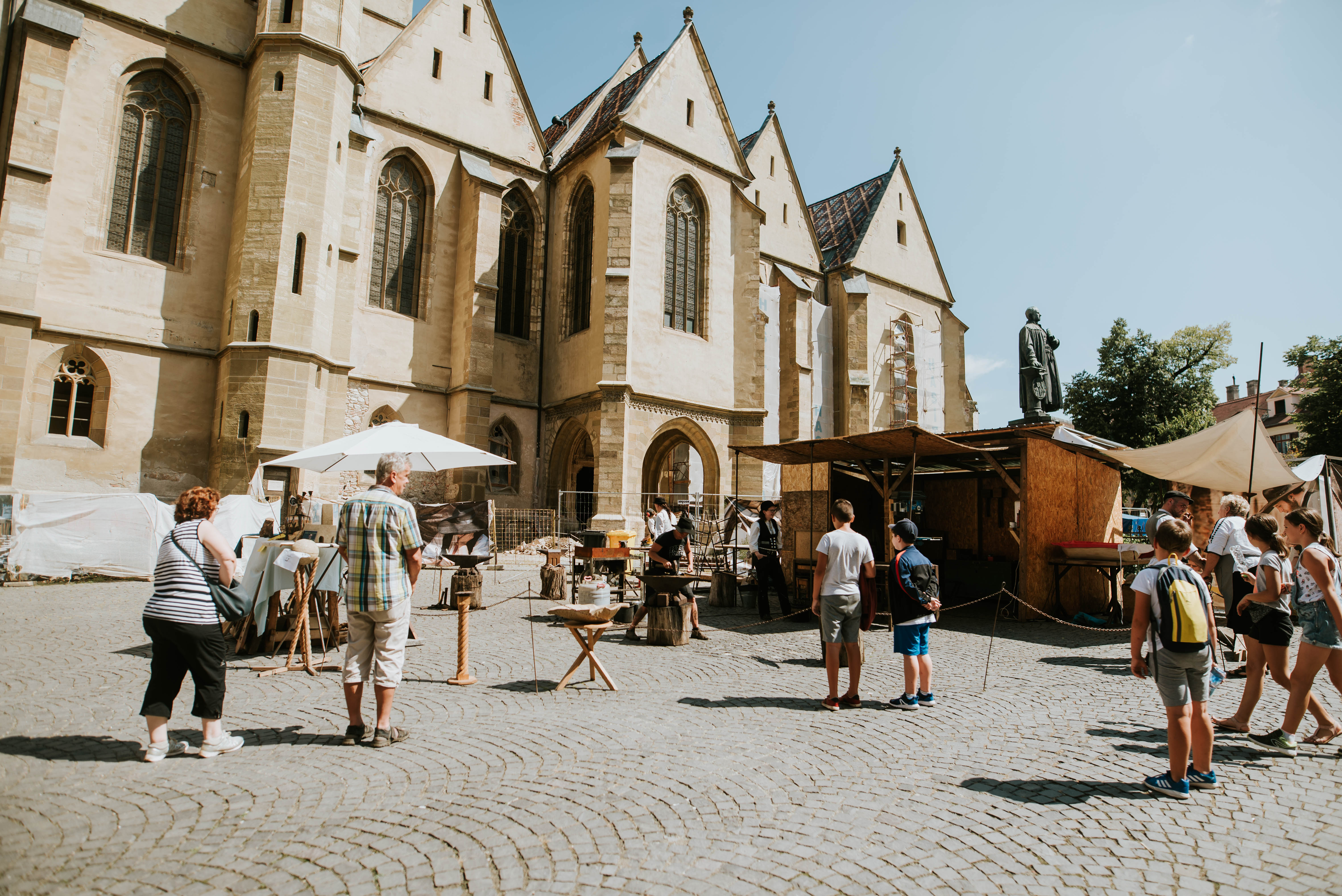 Die Wandergesellen nehmen Restaurierungsarbeiten an der evangelischen Stadtpfarrkirche vor, während Besucher sie beobachten.© Deutsche Gesellschaft e.V. Die Wandergesellen nehmen Restaurierungsarbeiten an der evangelischen Stadtpfarrkirche vor, während Besucher sie beobachten.© Deutsche Gesellschaft e.V.